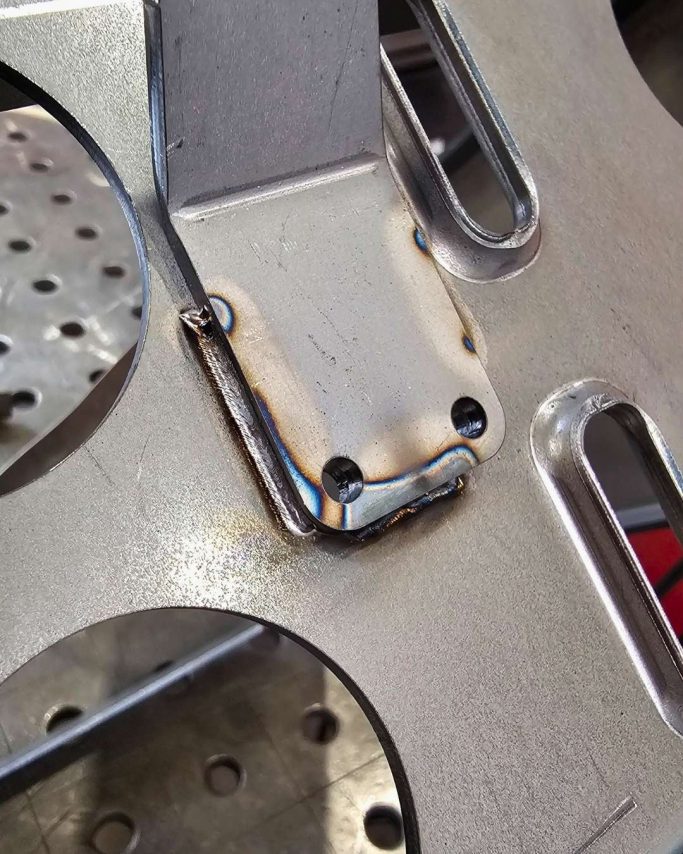 Detailansicht einer metallenen Halterung mit Schweißnähten auf einer Maschinenoberfläche.