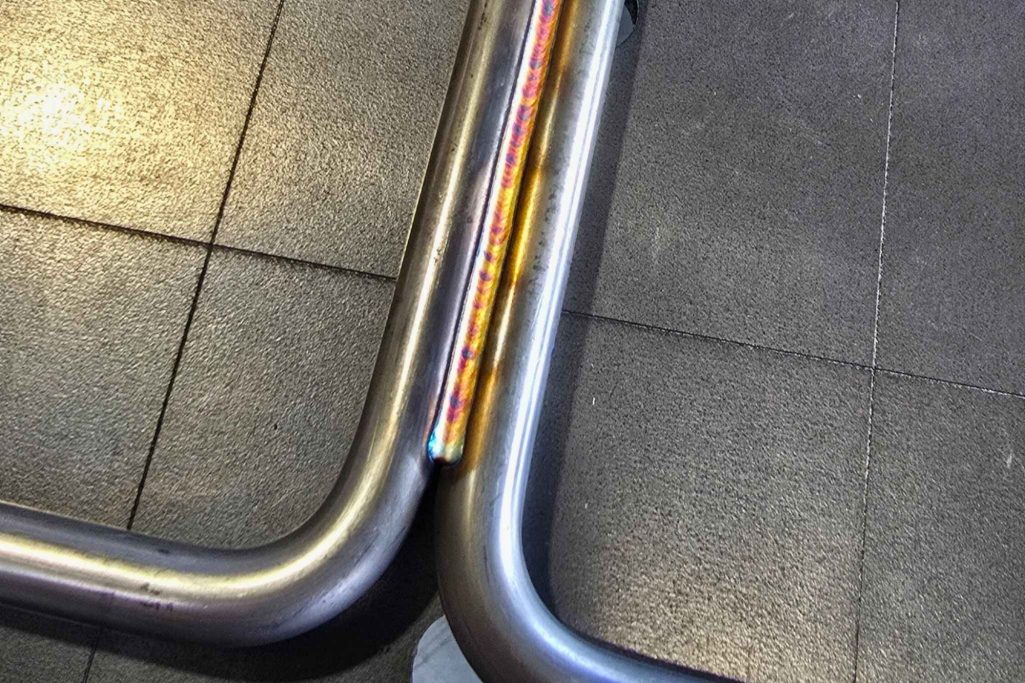 Zwei Metallrohre, die sich an einer Ecke treffen, auf einem dunklen Boden.