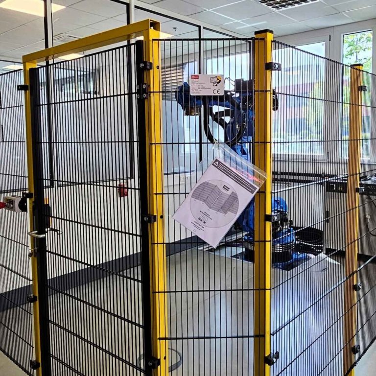 Sicherheitszaun um einen Roboterarbeitsplatz in einer modernen Werkstatt.