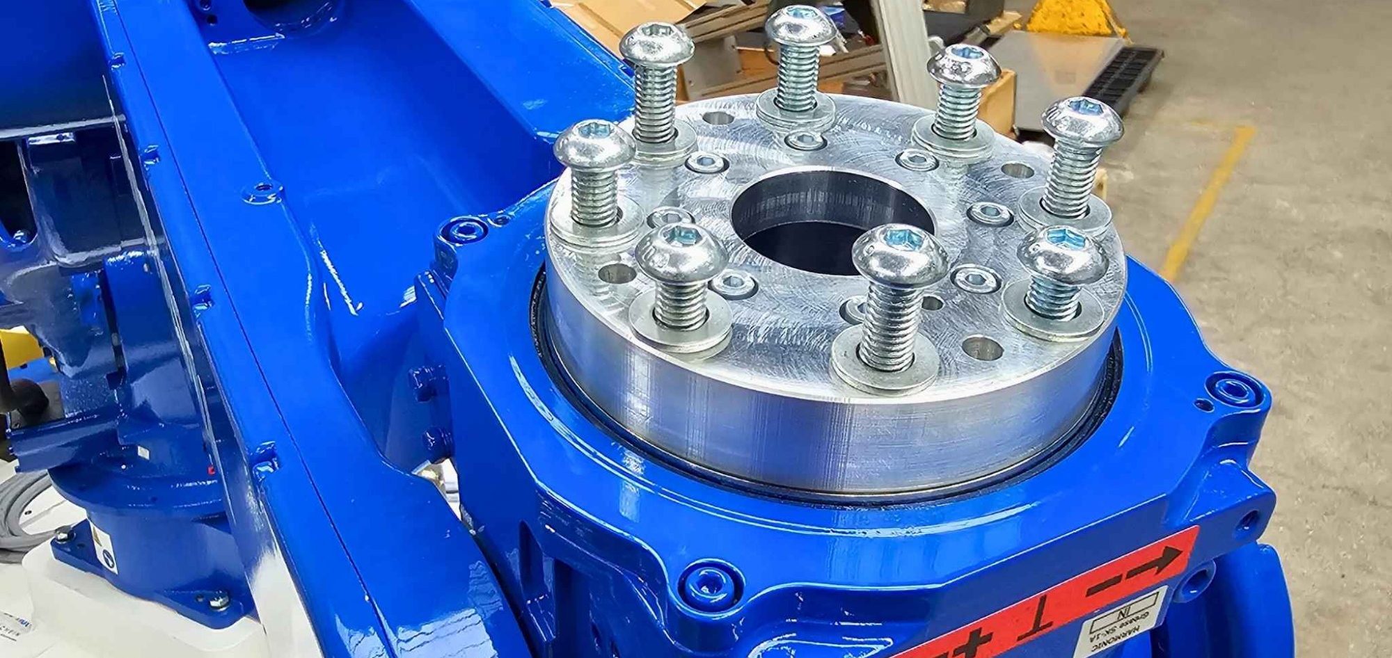 Blauer Yaskawa Roboter mit Metallplatte und Schrauben für mechanische Anwendungen.