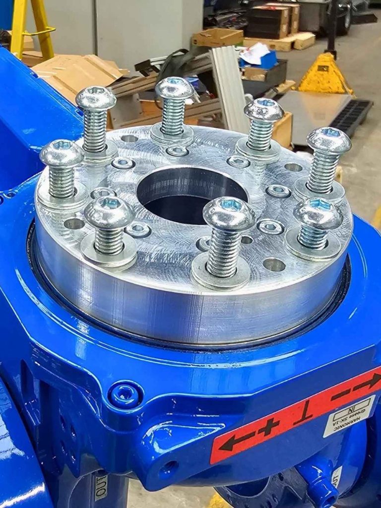 Nahaufnahme einer blauen Maschine mit einer metallischen Flanscheinheit und Schrauben.