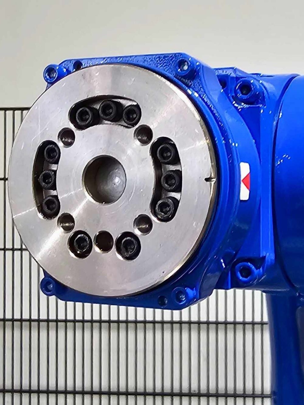 Blauer industrieller Roboterarm mit metallischem Drehkopf und mehreren Befestigungslöchern.