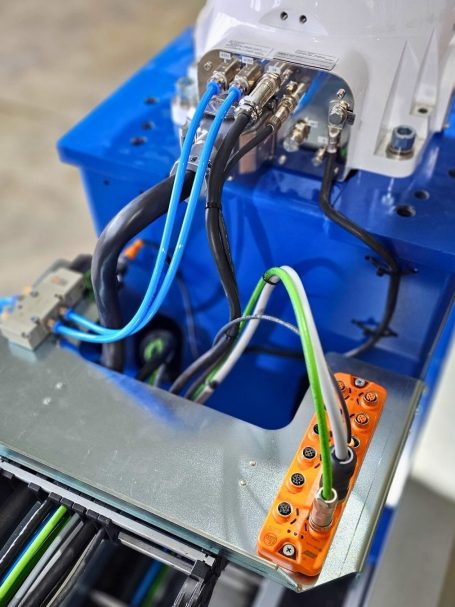 Drähte und Anschlüsse an einem technischen Roboter HC20DTP von Yaskawa, teils auf einer Metallplatte.