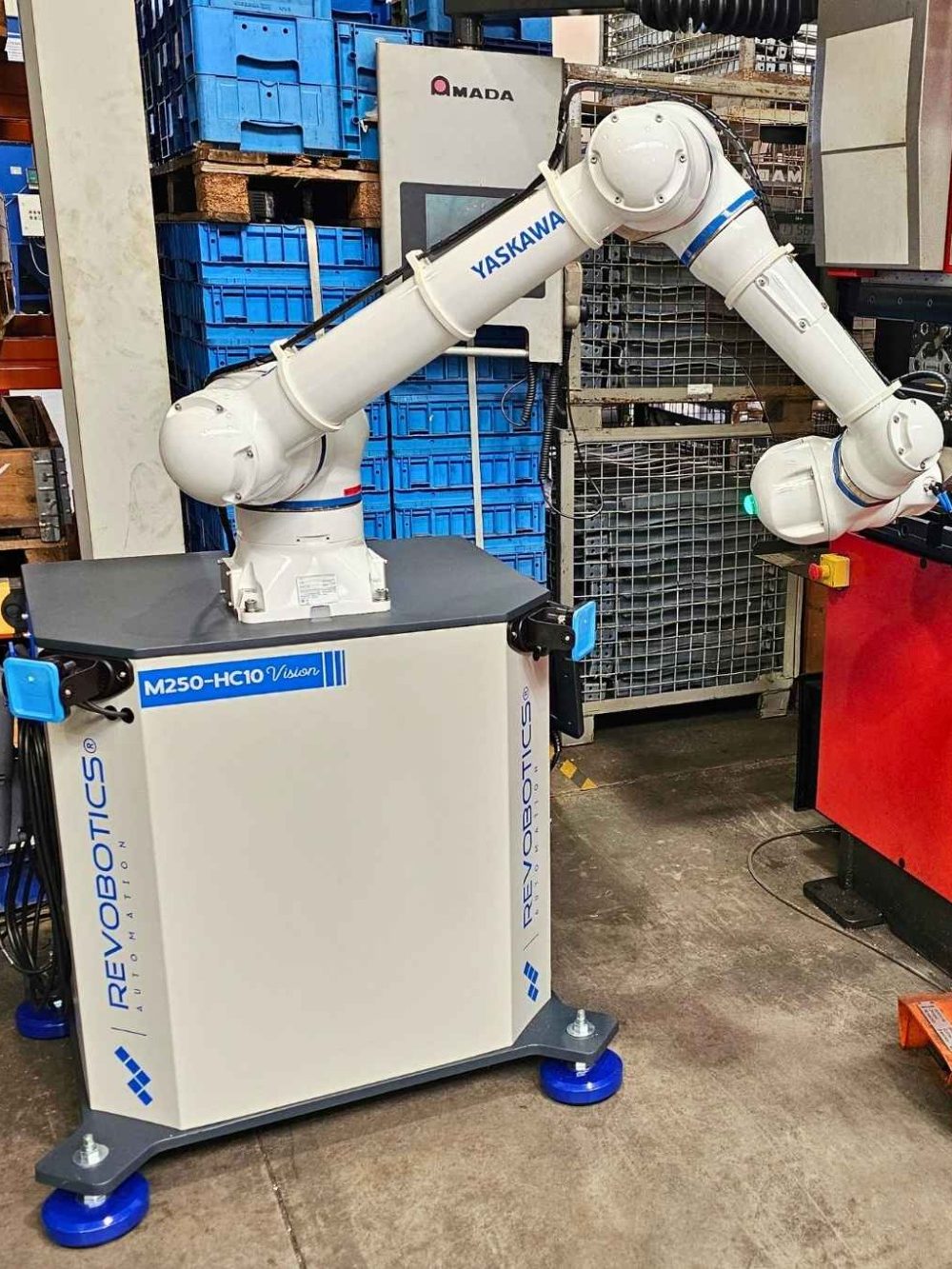 Industrieroboter mit Greifer in einer Werkstatt neben einer Abkantpresse.