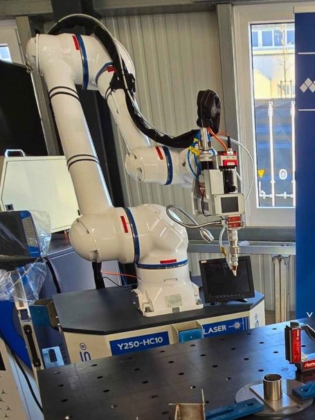 Industrieroboter für Laser-Schweißen und -Schneiden neben einem blauen Werbebanner.
